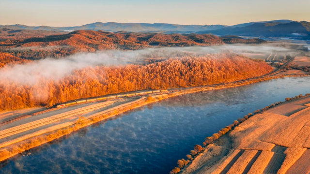 Golden autumn forest reflecting on a river with misty mountains in the background in China’s most beautiful autumn city.