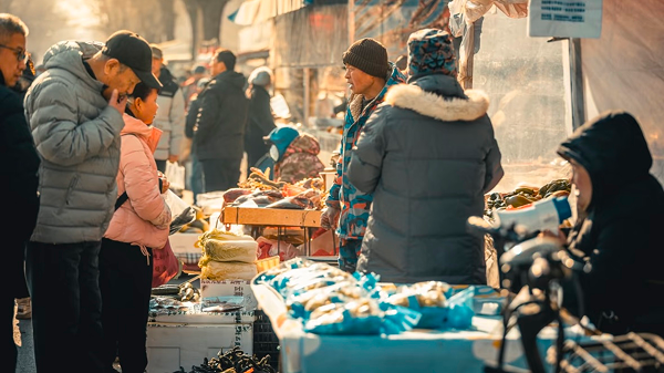 People shopping at a lively street market in Liaoning, showcasing local produce and vibrant community life.