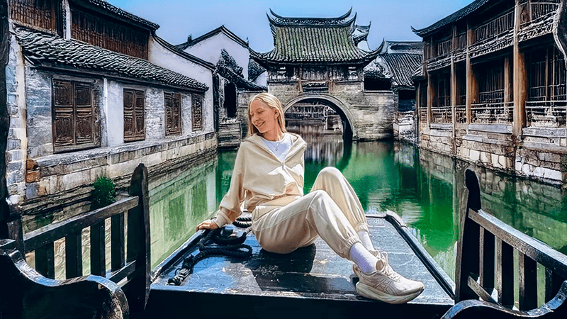 A female visitor enjoys the spring sunshine on a boat in Beijing's Gubei Water Town.