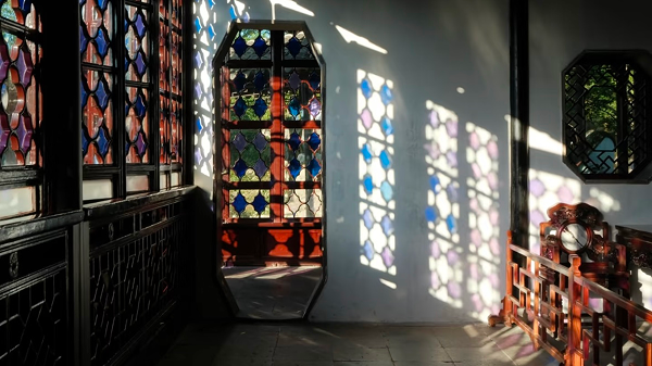 Colorful light reflections through stained glass windows in a classical Suzhou garden corridor