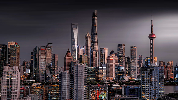 Shanghai Tower and iconic Lujiazui skyline illuminated at night under a dramatic sky.