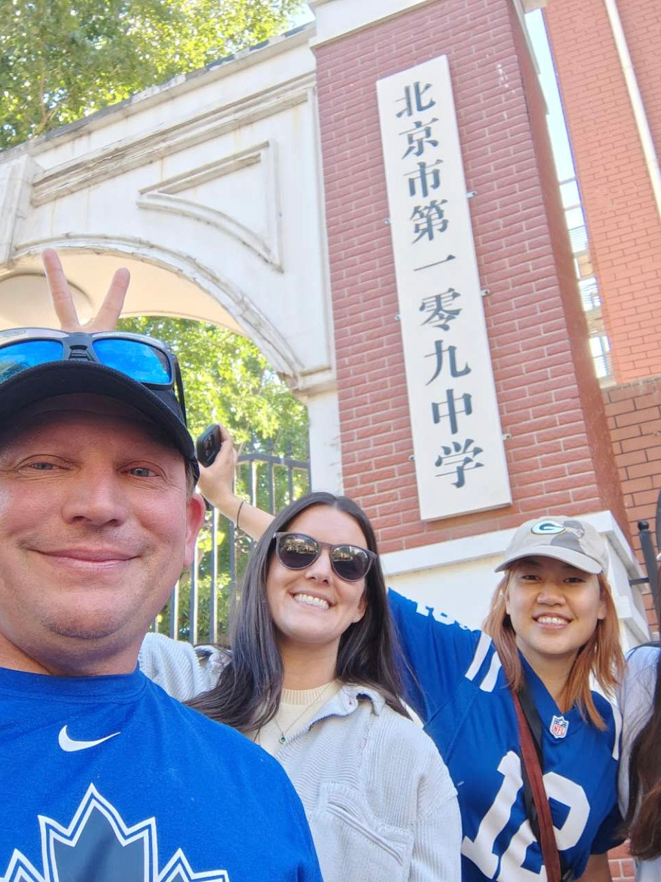 Travelers smiling in front of a Beijing local high school gate, exploring daily life and education culture in a traditional neighborhood