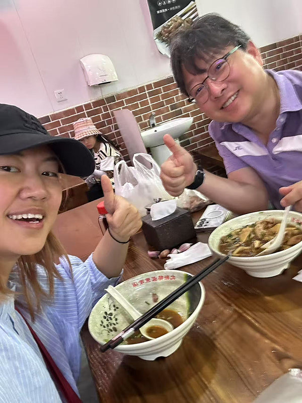 Two locals enjoying bowls of beef noodles in a cozy Beijing noodle restaurant, highlighting authentic food experiences