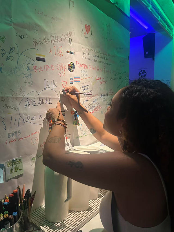 Visitor writing messages on a colorful wall inside a creative bar in Chengdu, highlighting artistic expression and nightlife culture
