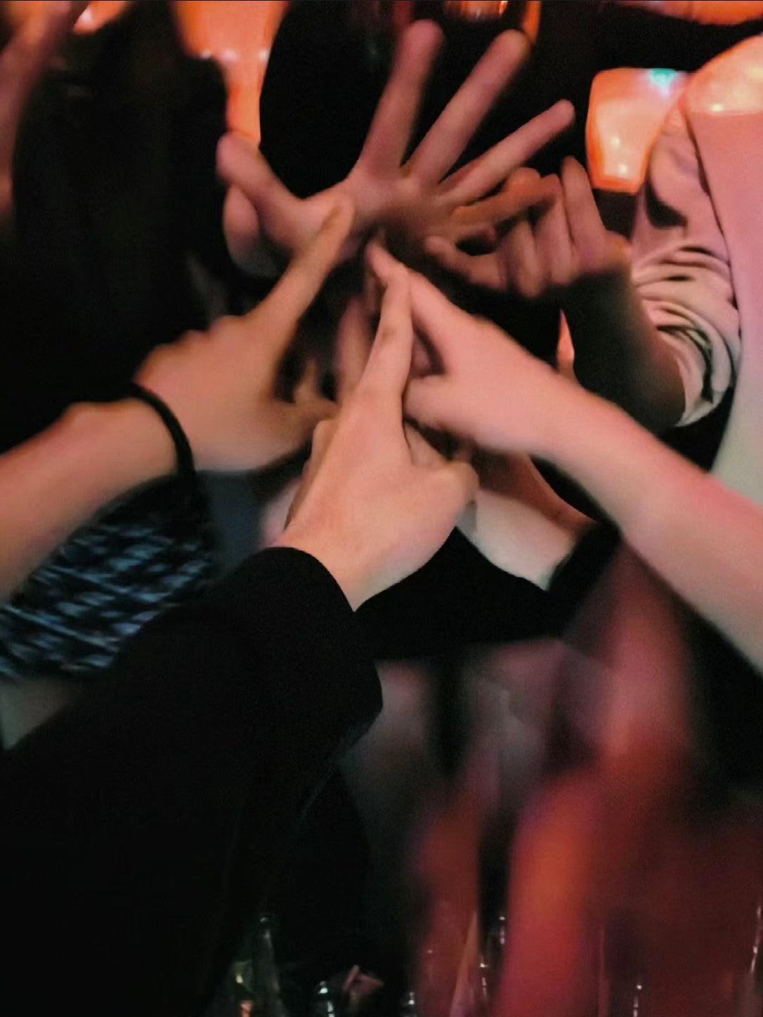 Friends raising their hands together in celebration at a lively bar, symbolizing fun nightlife.