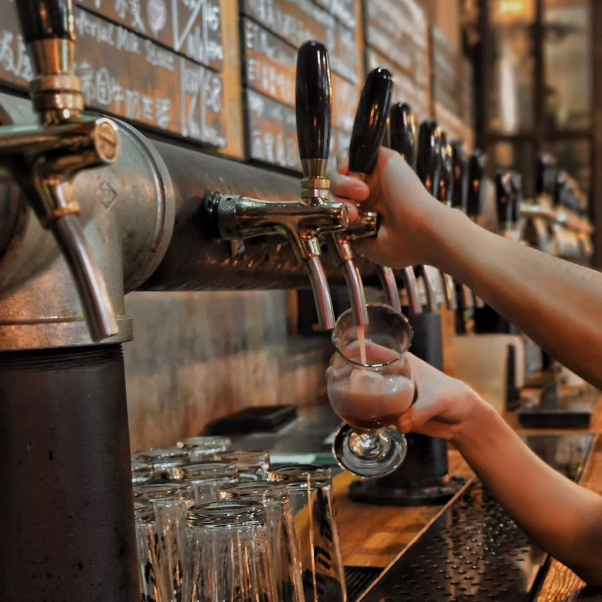 Close-up of a bartender pouring craft beer from a tap at a local brewery in China.