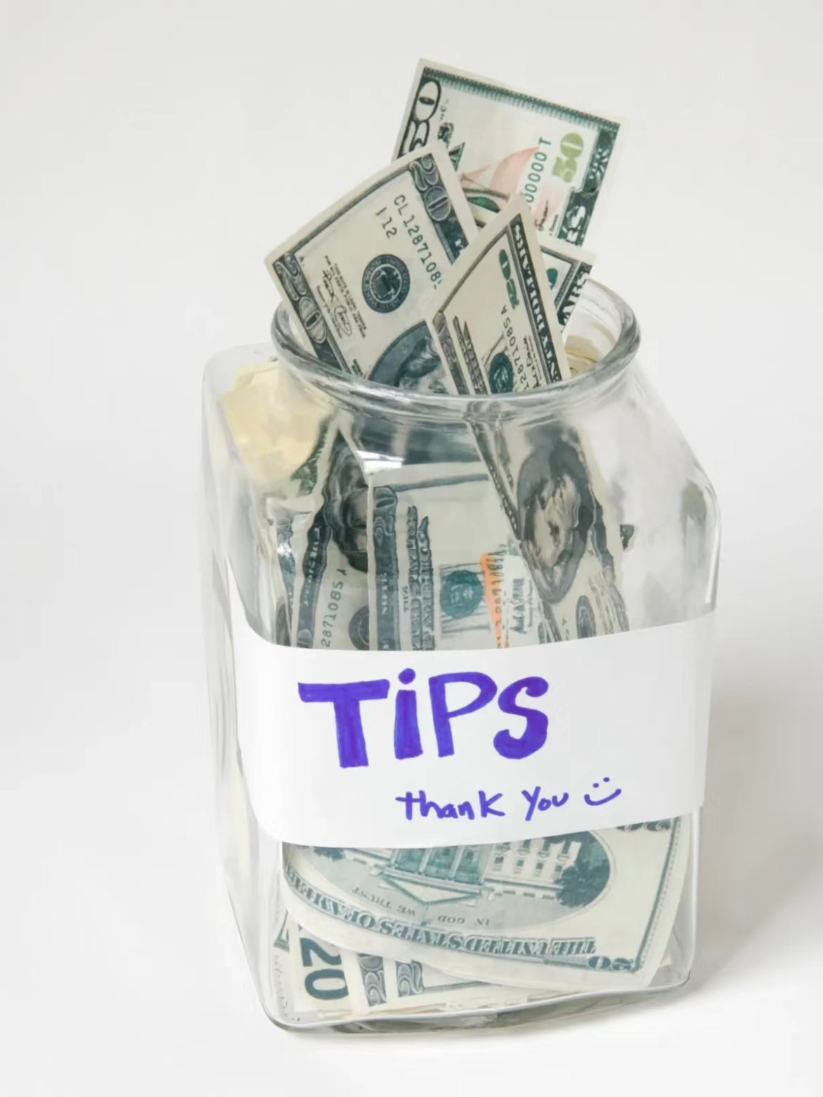A glass tip jar filled with dollar bills, labeled 'TIPS Thank You,' symbolizing gratitude and support for local experiences.