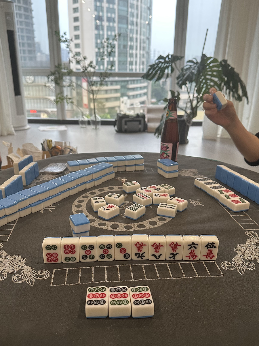 Playing mahjong in a high-rise Beijing apartment with panoramic city views, part of an immersive local game experience