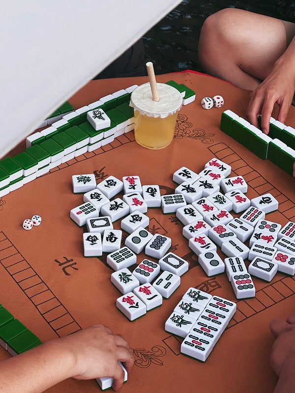 Mahjong tiles scattered during a vibrant game session with green tiles and milk tea, reflecting Beijing’s social tea culture