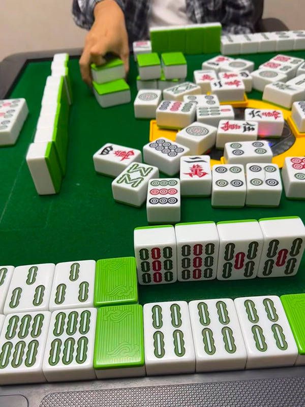 Close-up of a player organizing vibrant green mahjong tiles during a game in Beijing, highlighting strategy and playfulness