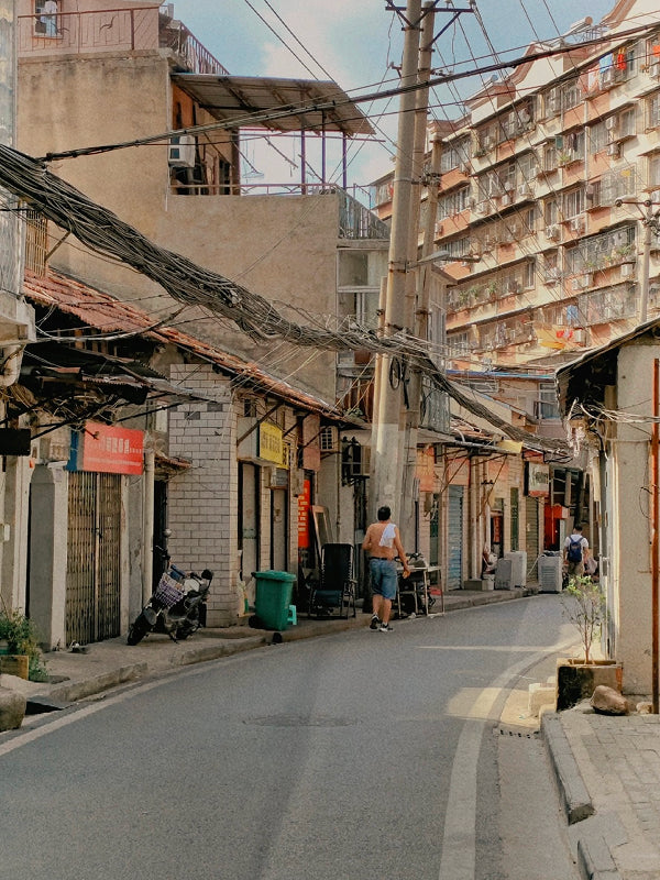Scene of everyday life in a bustling back alley in Wuhan, with hanging laundry, air conditioners, and locals going about their day