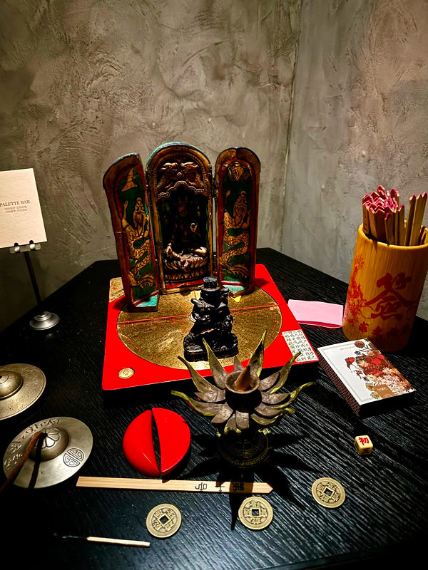 Authentic Taoist divination altar with deity figures, incense holder, oracle sticks, and Chinese coins in a Chengdu bar