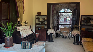 Interior of Master of the Nets Garden residence with antique piano, wooden shelves, and traditional Chinese furniture.