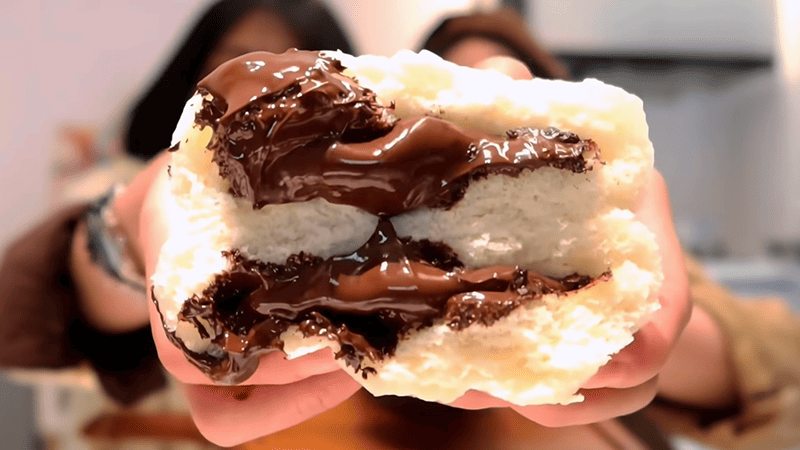 A girl is holding a chocolate straight foot in her hands.