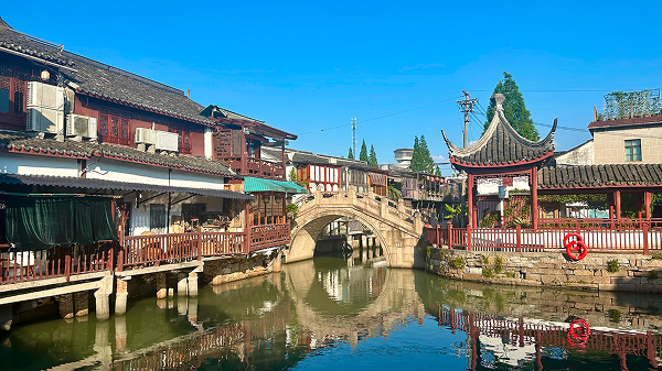 Traditional-style bridge over the canal in Zhujiajiao water town, Shanghai — a picturesque view that hides its modern reconstruction beneath old aesthetics.