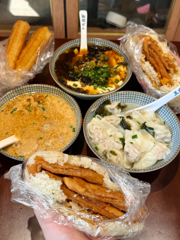 Assorted Hangzhou street breakfast including youtiao, savory tofu pudding, and sesame pancakes