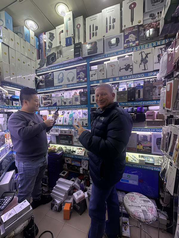 Local guide explaining gadgets to visitor inside Huaqiangbei electronics mall in Shenzhen