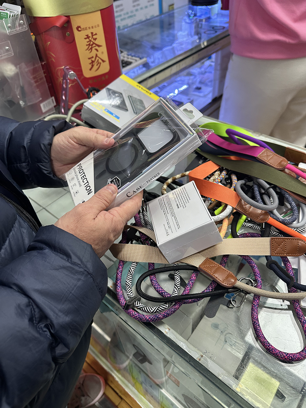 Traveler inspecting smartphone accessories and cables inside Huaqiangbei electronics market in Shenzhen