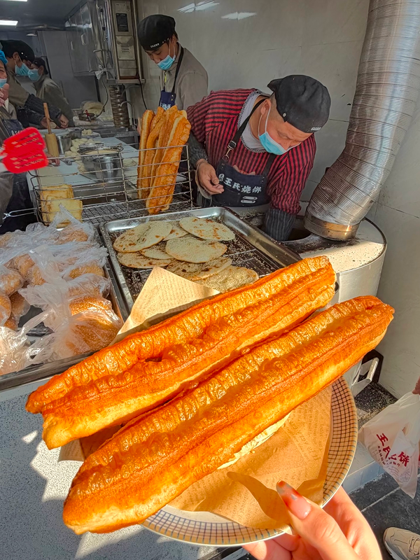 Crispy golden youtiao fried dough sticks at a traditional Hangzhou street vendor
