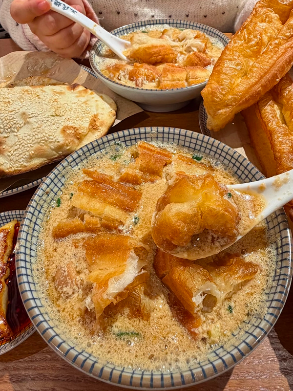 Sweet tofu pudding topped with syrup and crispy youtiao in Hangzhou local breakfast shop