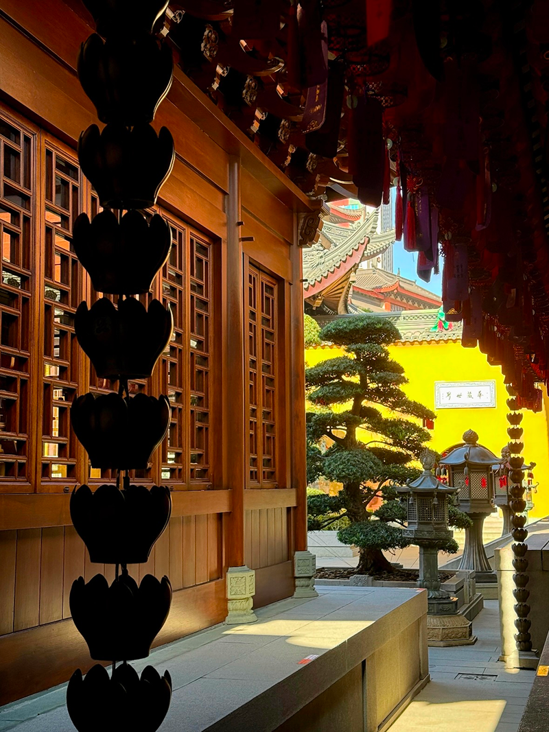 Sunlit wooden corridor at Jade Buddha Temple with traditional Chinese carvings
