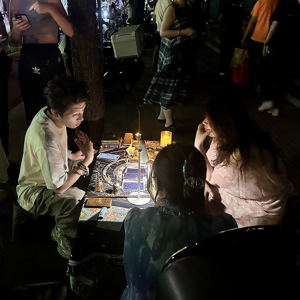 Night scene in Beijing with a street tarot reader conducting a mystical session under soft candlelight.