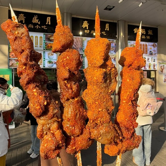 Close-up of four heavily seasoned lamb skewers from a Muslim street food vendor in Niujie.