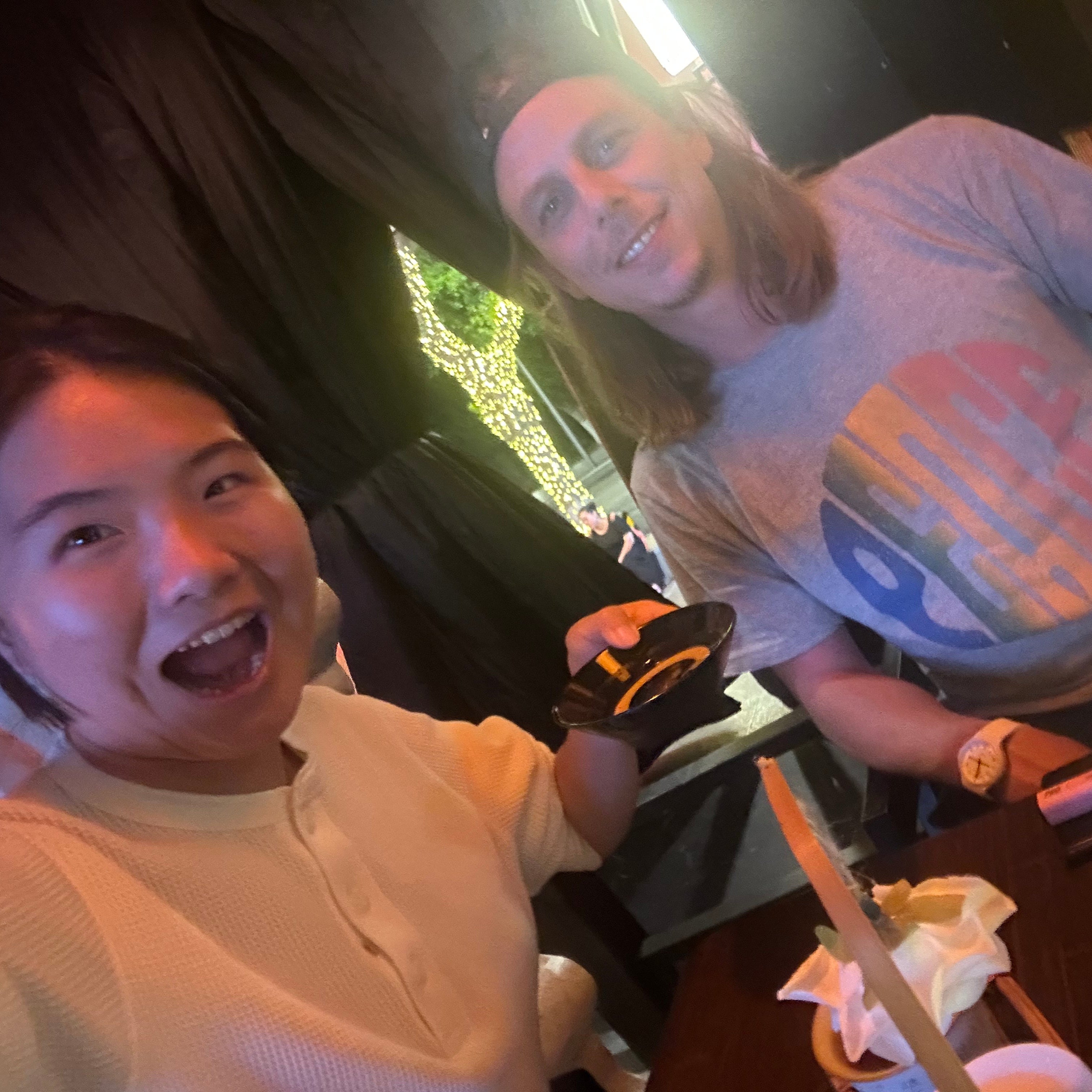 Two friends enjoying drinks at a trendy Chengdu bar decorated with glowing lights during a night out.