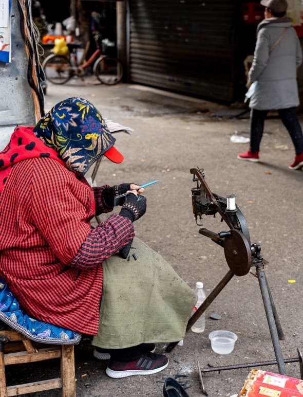 A woman artisan repairs leather shoes on the streets of Wuhan—keeping an age-old craft alive, one stitch at a time.
